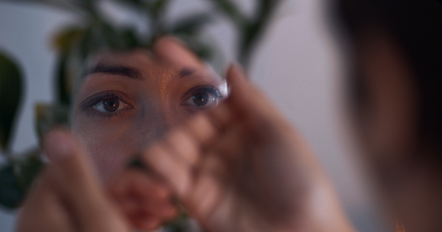 Uma mulher observa o próprio reflexo no espelho